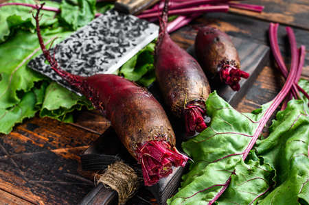 Purple beet on a cutting board. Dark wooden background. Top view.