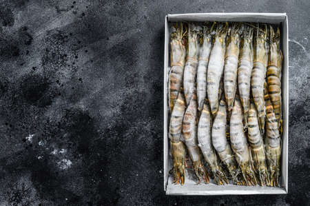 Package of frozen tiger prawns, shrimps. Black background. Top view. Copy space.の写真素材