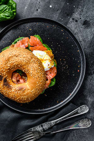 Smoked salmon bagel toasts with soft cheese, spinach and egg. Black background. Top view.の写真素材