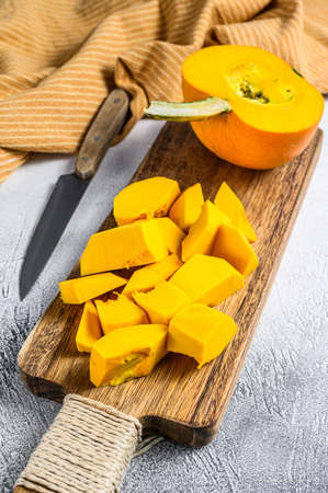 Raw pumpkin cubes on a cutting Board. White background. Top view.の写真素材