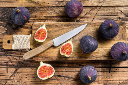 Sliced purple figs on a cutting Board. Wooden background. Top viewの写真素材
