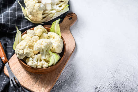 Raw cauliflower cut into pieces in wooden bowl. White background. Top view. Copy space.の写真素材