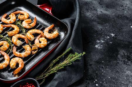 Fried king prawns, shrimps in a pan. Black background. Top view. Copy space.