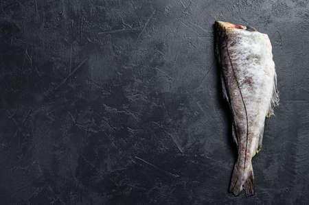 Raw haddock fish without a head. Black background. Top view. Copy space.