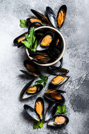 Raw fresh mussels in shells. The concept of cooking seafood. Gray background. Top view.