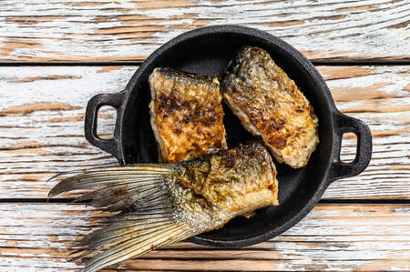 Roasted piece of silver carp. Wooden background. Top view.