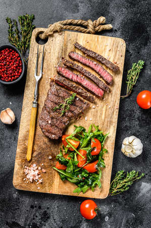 Grilled rump steak with spices on a chopping Board. Barbecue beef. Black background. Top viewの写真素材