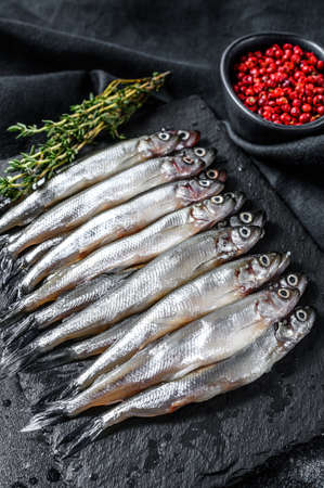 Raw small fish anchovies with pepper and thyme. Black background. Top view.の写真素材