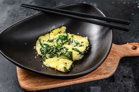 scrambled eggs with spinach and Parmesan cheese with sesame. Black background. Top view.の写真素材