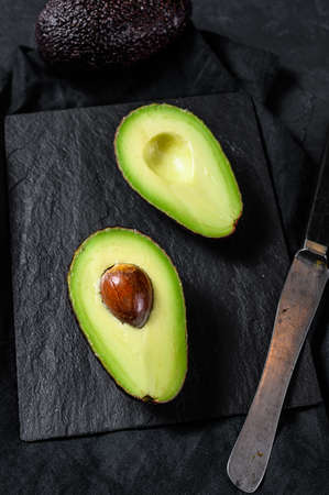 Sliced brown avocado. Black background. Top view.