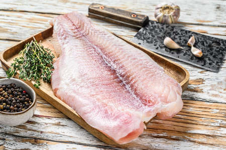 Raw fillet of pangasius fish. White wooden background. Top view. Copy space.の写真素材