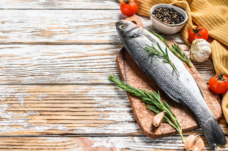 Fresh raw sea bass fish with herbs. White background. Top view. Copy space.の写真素材
