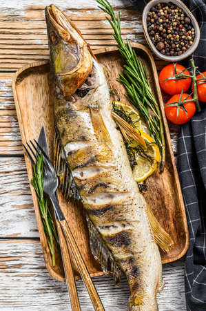 Baked Zander, walleye fish with herbs and lemon. White wooden background. Top view.の写真素材