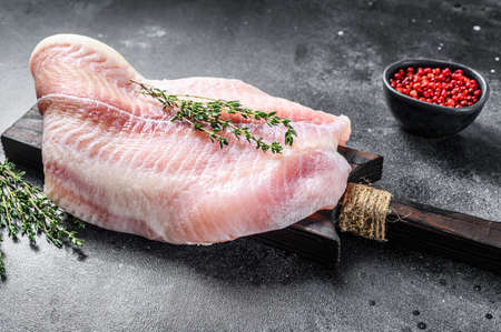 Raw fillet of white fish catfish on a cutting board. Black background. Top view.の写真素材