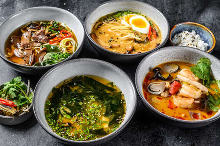 Assorted traditional Asian soups. Miso, Ramen, Tom Yam, Pho Bo. Black background. Top view.の写真素材