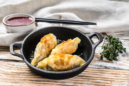 Fried Japanese gyoza dumplings in a pan. White wooden background. Top view.の写真素材
