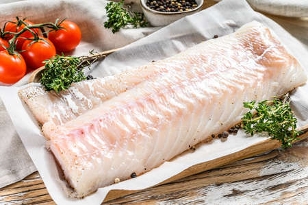 Fresh Raw Cod loin fillet with thyme. White wooden background. Top view.の写真素材