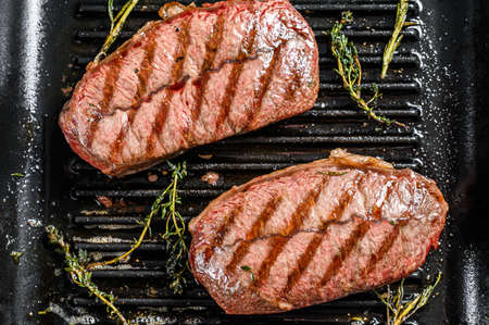 Grilled meat Top Blade steaks in a frying pan. Gray background. Top view.の写真素材