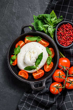 Caprese salad with burrata mozzarella, cherry tomatoes and Basil. Black background. Top view.の写真素材
