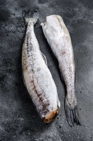 Raw Pollock fish ready to cook. Black background. Top view.