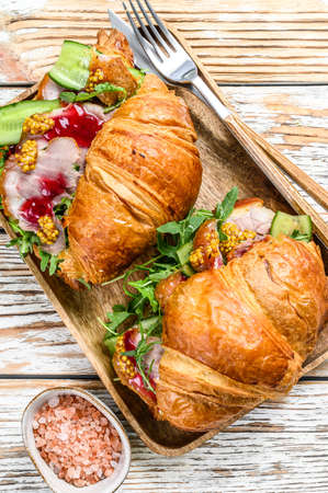 Sandwich croissant with ham and cheese on wooden board. White wooden background. Top view.の写真素材