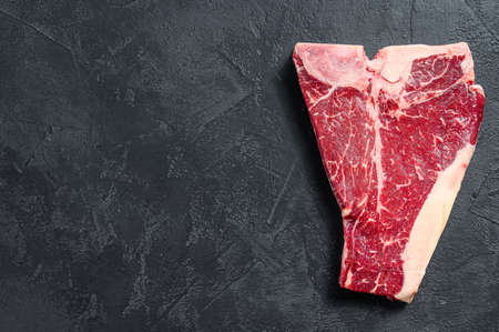 Thick Raw T-Bone Steak. Black background. Top view. Copy space.の写真素材
