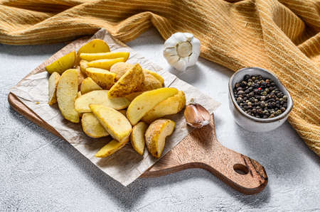 Frozen potato wedges on a cutting board. Recipe for French Fries. White background. Top view.の写真素材