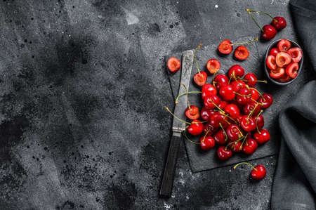 Cherries on black cutting board. fresh ripe cherries. Black background. Top view. Copy space.の写真素材