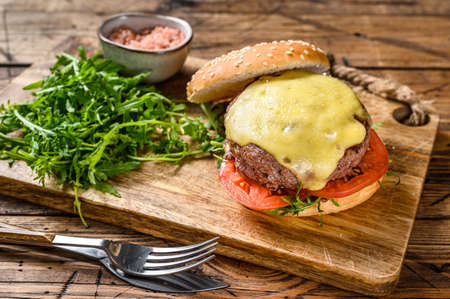 Big sandwich burger with beef, tomato, cheese and arugula. wooden background. Top view.の写真素材