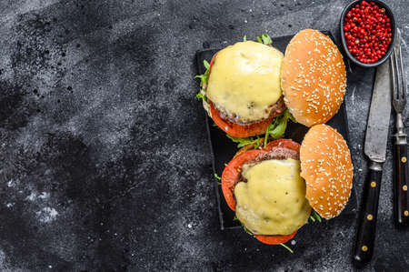 Grilled homemade burgers with beef, tomato, cheese, cucumber and lettuce. Black background. Top view. Copy space.の写真素材