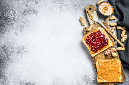 Peanut butter and jelly on white bread toasts. White background. Top view. Copy space.の写真素材