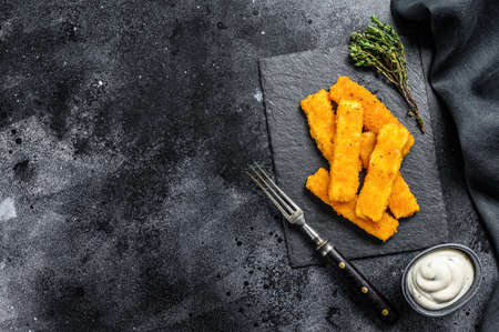 Crispy fried fish fingers with breadcrumbs served with sauce tartar. Black background. Top view. Copy space.の写真素材