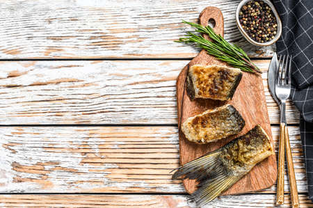 Grilled river fish silver carp on a cutting board. Wooden background. Top view. Copy space.の写真素材