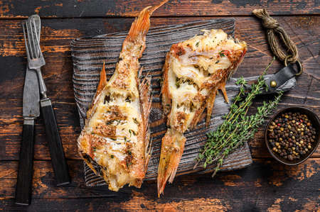 Grilled Red Sea perch or grouper. Dark wooden background. Top view.