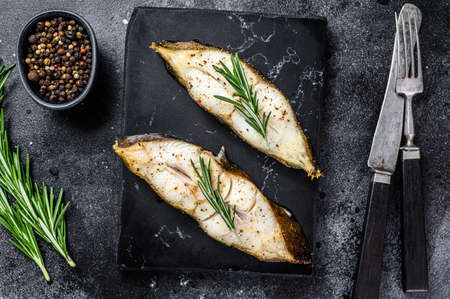 Baked halibut fish steak. Black background. Top view.