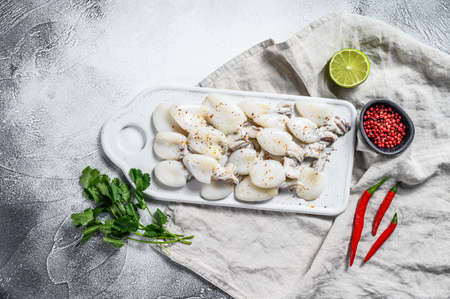 Fresh cuttlefish with chili pepper and parsley on a cutting Board. Gray background. Top view. Copy space.の写真素材