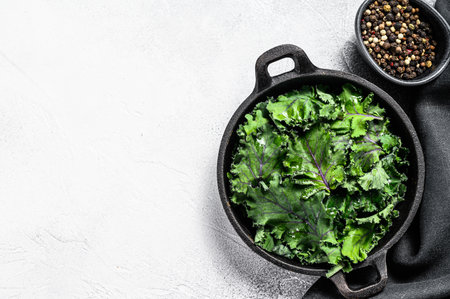 Raw Green Kale salad in a pan. Organic Vegetarian food. White background. Top view. Copy spaceの写真素材