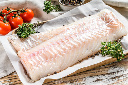 Fresh Raw Cod loin fillet with thyme. White wooden background. Top view