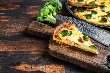 Quiche sliced tart with salmon, spinach and cream. Dark wooden background. Top view. Copy space.の写真素材