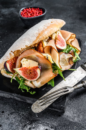 Sandwich with baguette, ham, fig, arugula and prosciutto meat. Black background. Top view.の写真素材