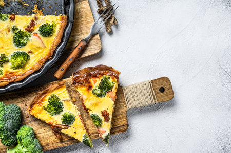 Sliced tart with salmon, broccoli and cream on a wooden cutting board. White background. Top view. Copy space.の写真素材