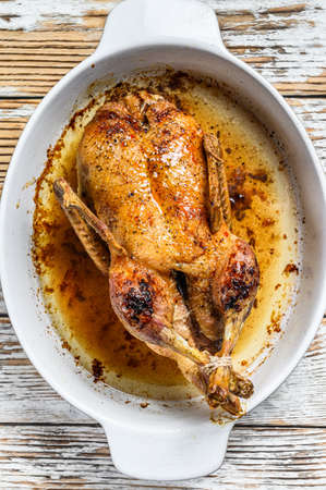 Baked whole farm duck in a baking dish. White wooden background. Top view.の写真素材