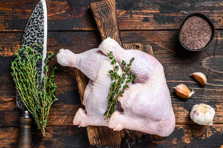 Raw chicken legs on a cutting board. Dark wooden background. Top view.の写真素材