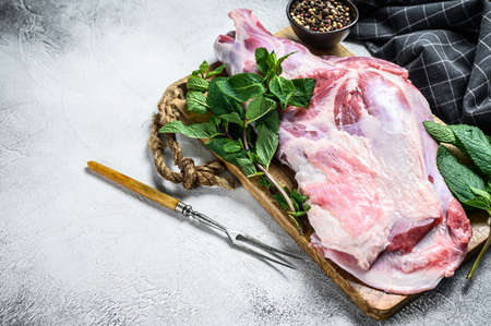 Raw goat shoulder meat ready for baking with garlic, mint. White background. Top view. Copy space.の写真素材
