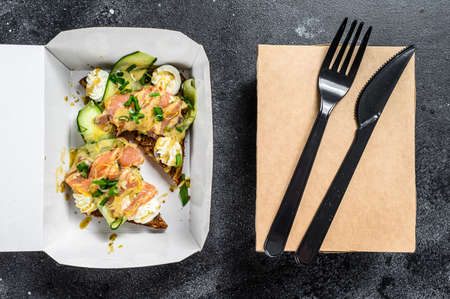 Food delivery paper box for breakfast with sandwich. Black background. Top view.