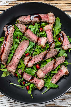French beef pepper steak with arugula leaves salad. White wooden background. Top view.の写真素材