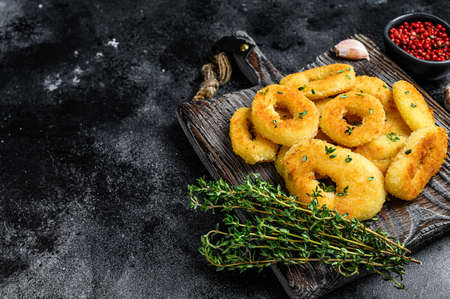 Deep fried squid calamari rings breaded on a cutting board. Black background. Top view. Copy space.の写真素材