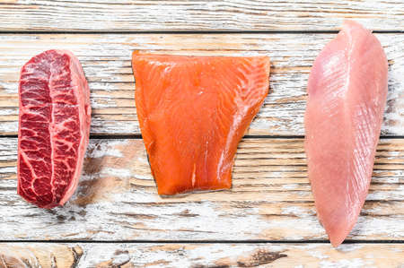 Raw salmon, beef and Turkey. Fresh organic meat. White wooden background. Top view.の写真素材
