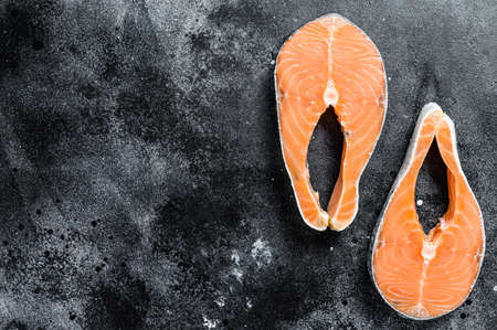 Raw salmon steak, organic fish. Black background. Top view. Copy space.