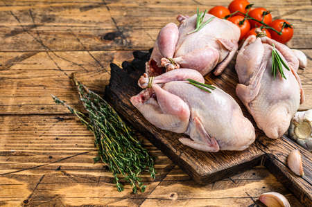 Raw quails on a cutting board. wooden background. Top view. Copy space.の写真素材